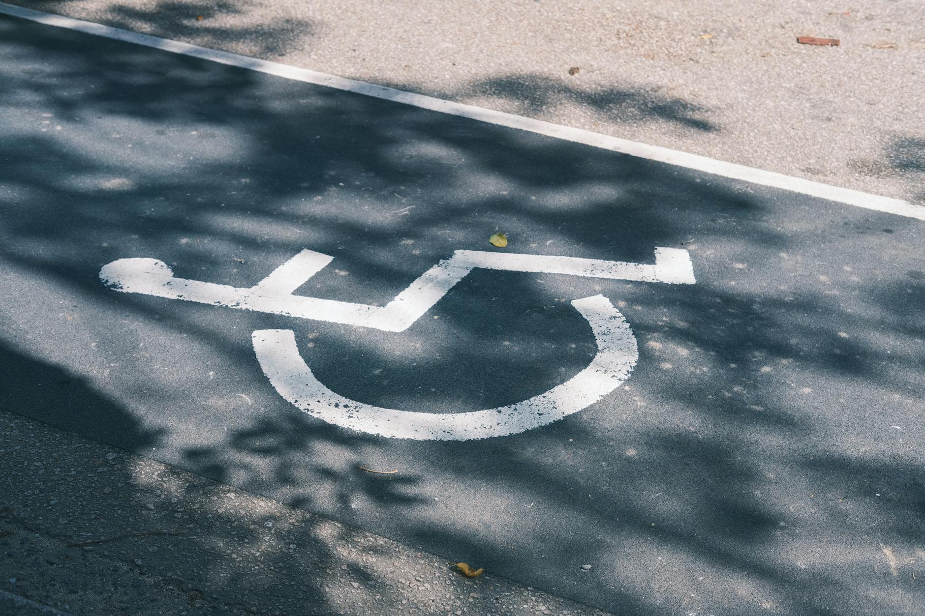 Znak miejsca parkingowego dla osób z niepełnosprawnością na asfalcie
